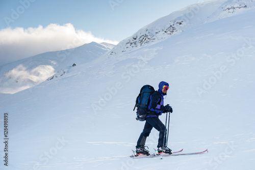 Tourist with a backpack goes to the winter mountains to ski tour