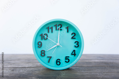 Green clock on a wooden table on a white background.