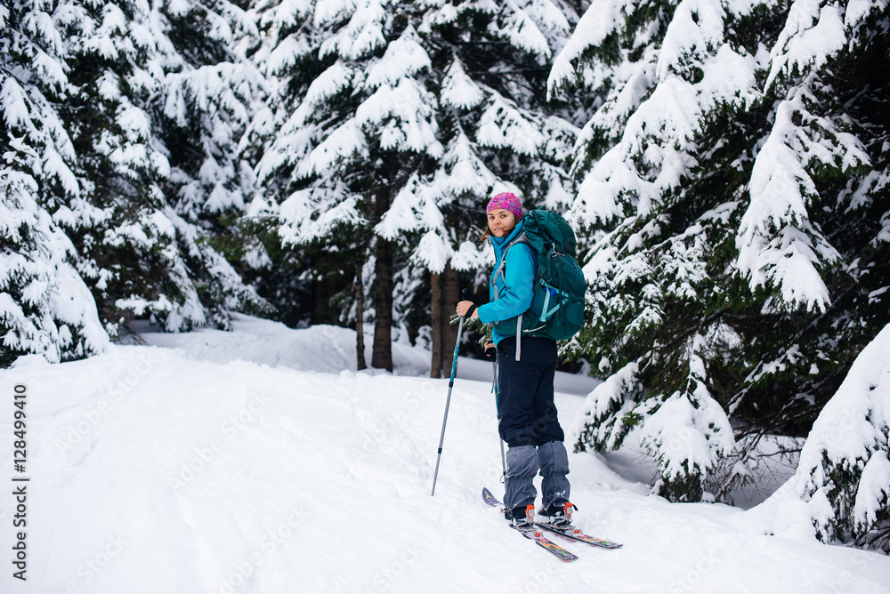 Girl in bright clothes with a backpack is traveling on ski tours