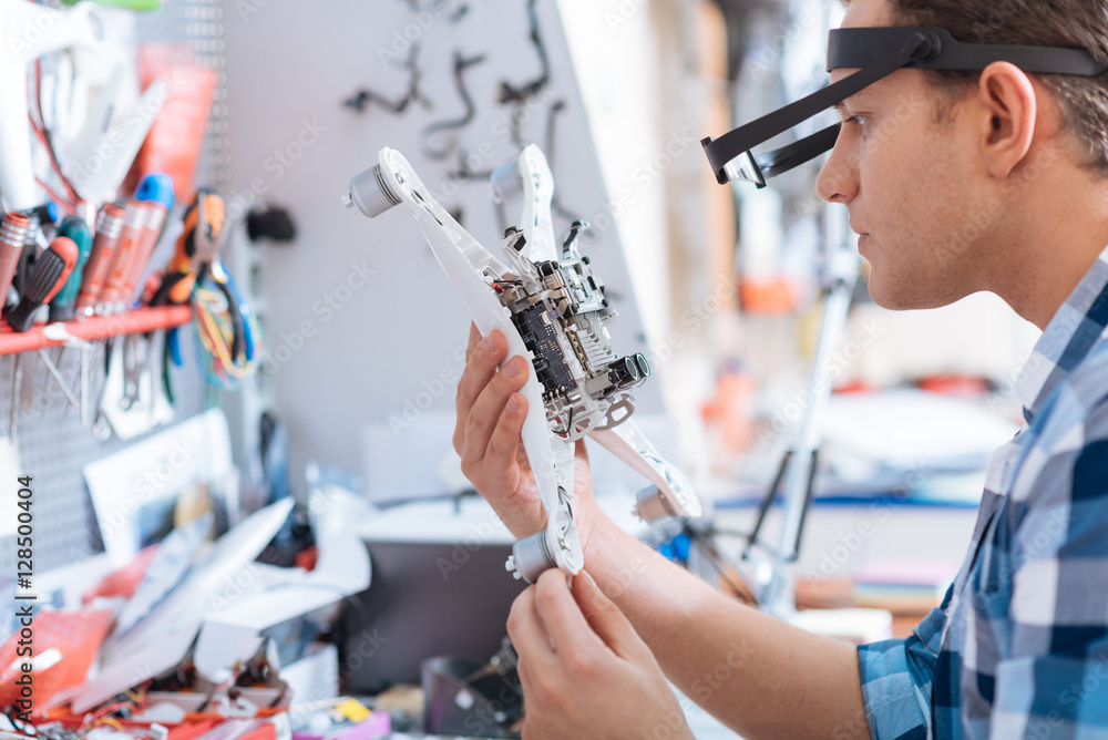 Delighted man discovering drone detail in workroom Delighted man discovering drone detail in workroom