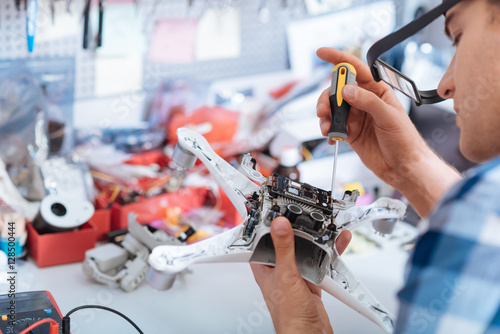 Concentrated man repairing drone detail with screwdriver