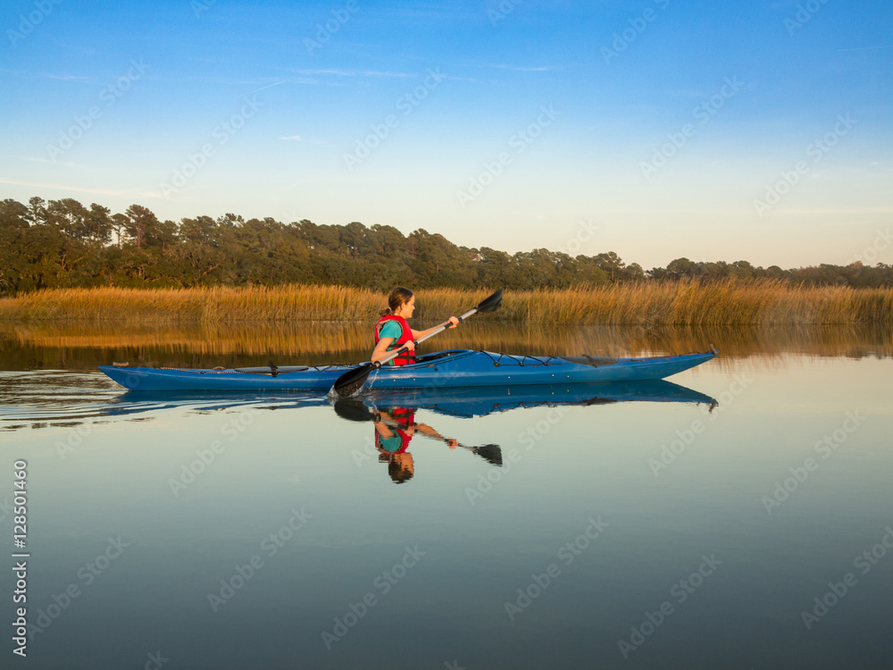 Teen kayaking through glassy water
