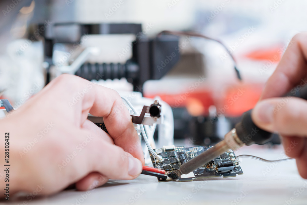 Macro close up of mans hands soldering drone chips Macro close up of mans hands soldering drone chips