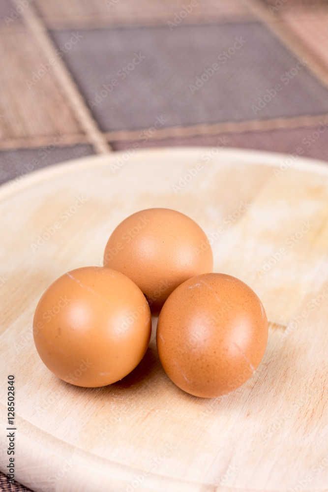 Three raw domestic chicken eggs on the wooden board Three raw domestic chicken eggs on the wooden board