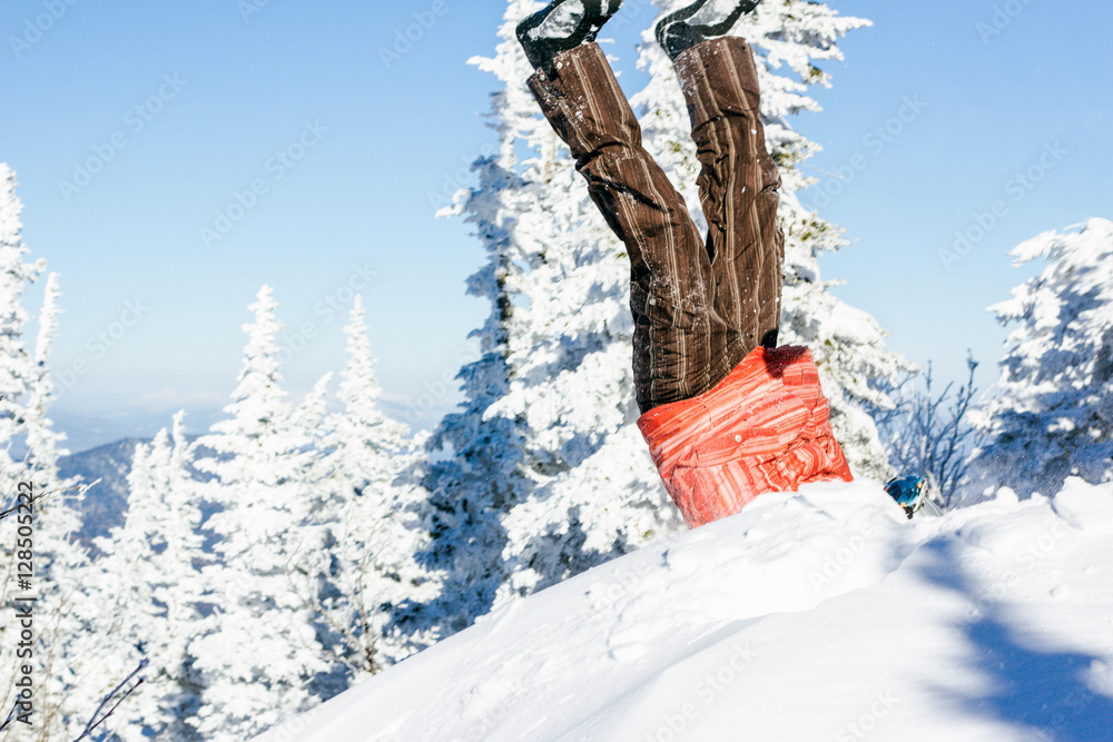 Legs of a snowboarder stuck in deep snow upside down