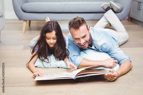 Father and daughter looking in picture book on floor