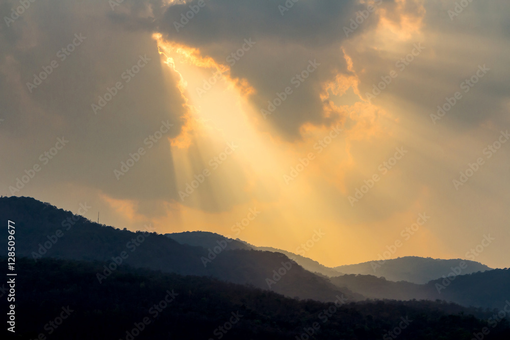 Clouds and golden sunbeam over mountain at evening