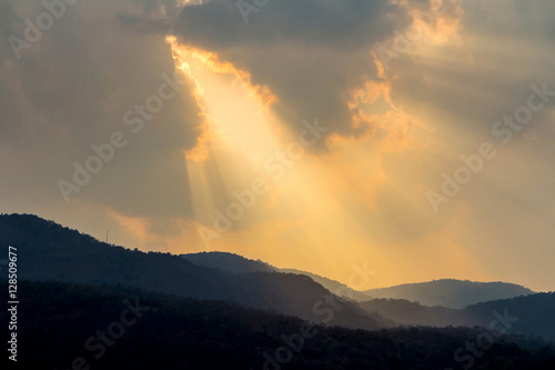 Clouds and golden sunbeam over mountain at evening