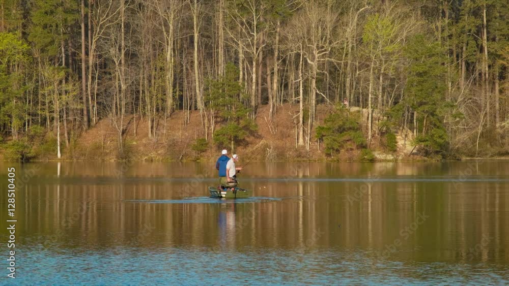 Men Fishing in a Boat on Lake Johnson Close-up in Raleigh North Carolina with Golden Morning Sunshine and a Forest Tree line Background Men Fishing in a Boat on Lake Johnson Close-up in Raleigh North Carolina with Golden Morning Sunshine and a Forest Tree line Background