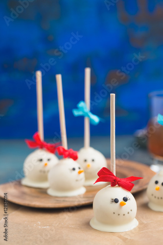 Festive snowman chocolate cake pops against blue background.