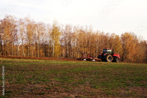 Tractor in the field plows the earth in sunny autumn day