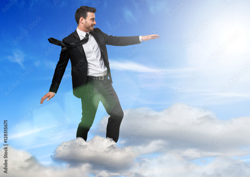 Young businessman flying over a cloud Young businessman flying over a cloud