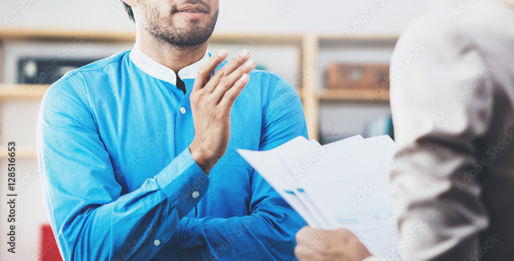 Obraz premium Closeup photo of two coworkers making a great business discussion in modern office.Successful confident hispanic businessman talking with young woman. Horizontal wide, blurred background.