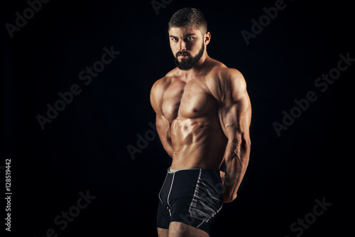Handsome muscular bodybuilder posing over black background. © satyrenko