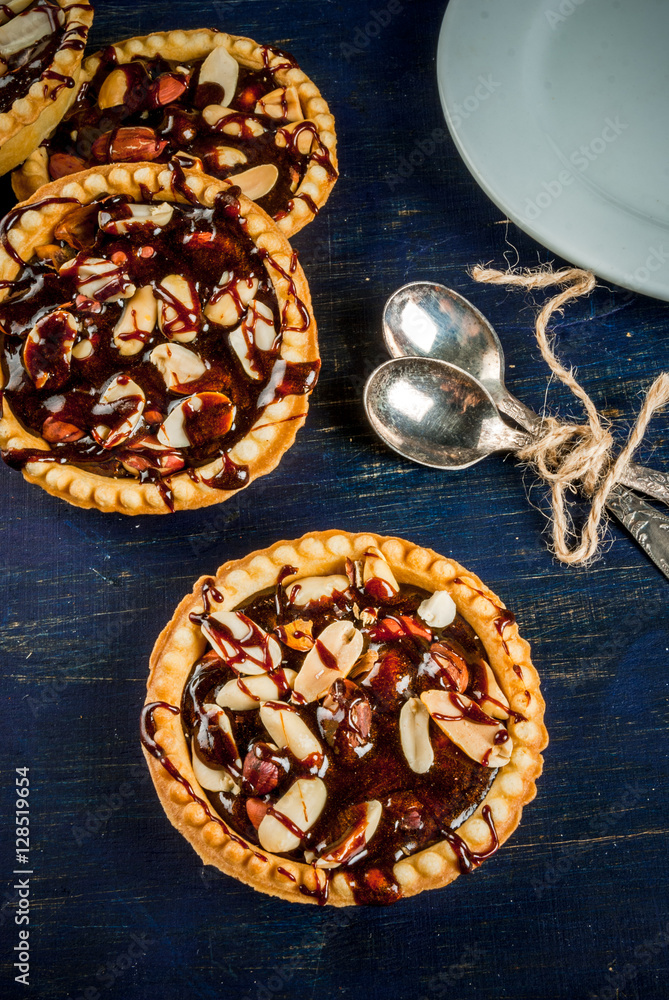 Fototapeta premium Mini tarts with nuts and caramel on a rustic background, top view, copy space