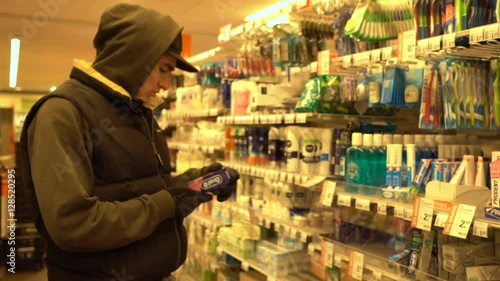 Young caucasian man shopping in a Supermarket and browsing products. Man choosing cosmetics, Toothpaste