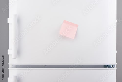Blank light pink sticky paper note on white refrigerator