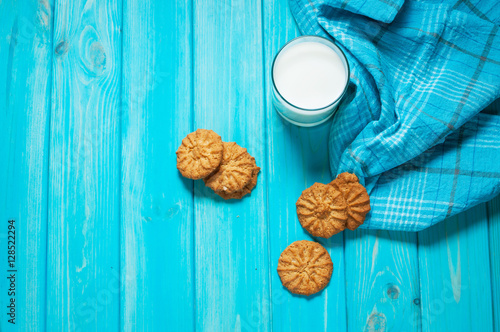 Cup of milk and cookies on a blue wooden table.