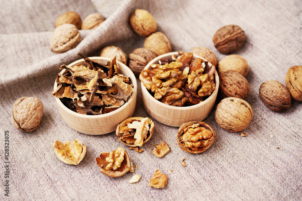 Kernels and partitions of walnut in wooden bowls and the whole walnuts on a table. Walnuts Kernels and partitions of walnut in wooden bowls and the whole walnuts on a table. Walnuts