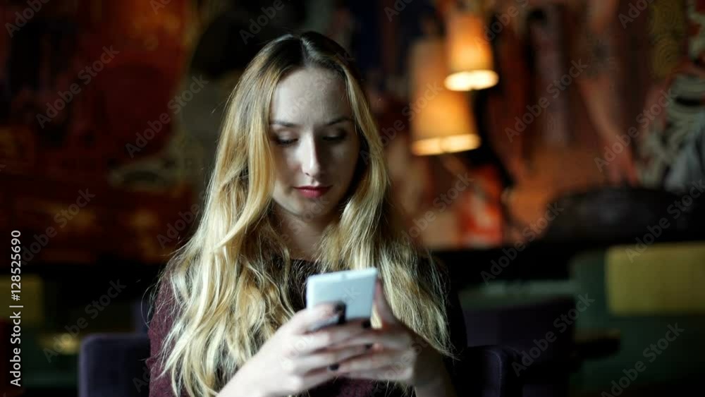 Girl looking absorbed while typing message on smartphone in the cafe
Girl looking absorbed while typing message on smartphone in the cafe