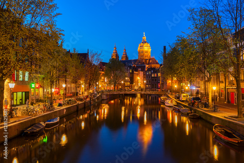 Church of St Nicholas and red lights quater over old town canal at night, Amsterdam, Holland