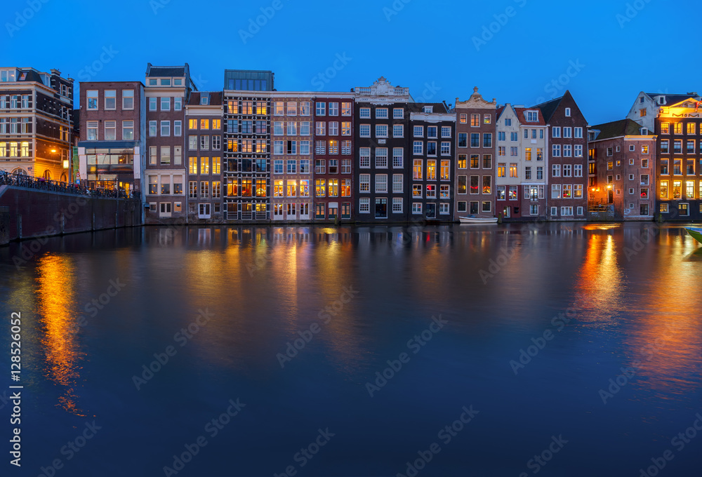 Houses facades over canal with reflections illuminated at night, Amsterdam, Netherlands, toned