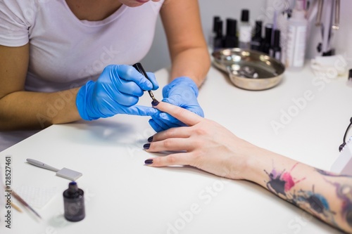 Manicurist master makes manicure on young woman hand