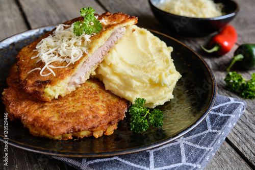 Fried pork cutlets coated in potato batter, studded with cheese and served with mashed potato