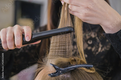 Closeup of hairdresser straightening the hair of a client
