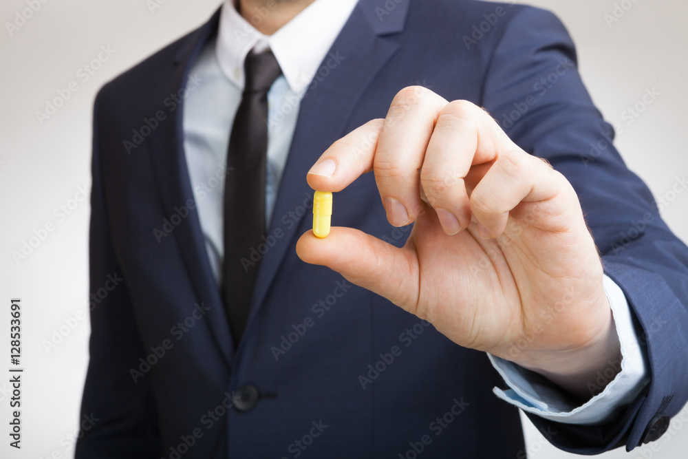 Fototapeta premium Businessman holding pill in hand
