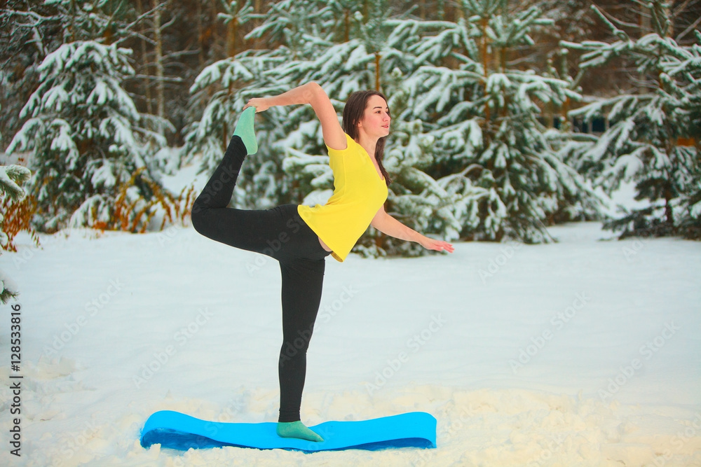 beautiful woman doing yoga outdoors in the snow