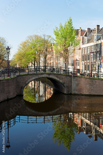 Historical bridge over canal with mirror reflections in water, Amstardam, Netherlands