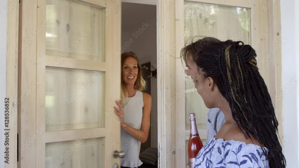 Couple greeting their dinner guests at the front door, shot on R3D Couple greeting their dinner guests at the front door, shot on R3D