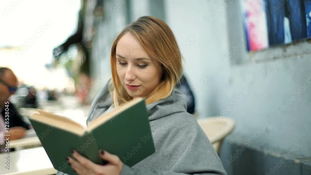 Girl smiling to the camera while sitting outdoors and reading book
Girl smiling to the camera while sitting outdoors and reading book