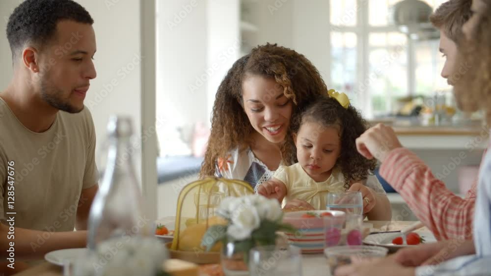 Couple, young girl and adult friends talk at kitchen table Couple, young girl and adult friends talk at kitchen table