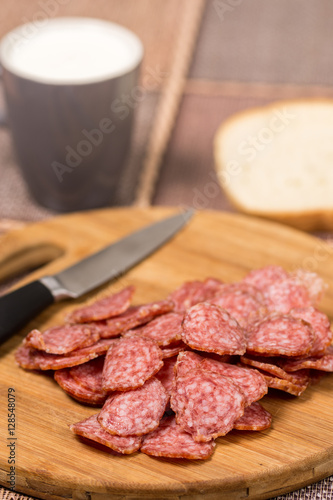 Sliced sausages on the wooden board with bread