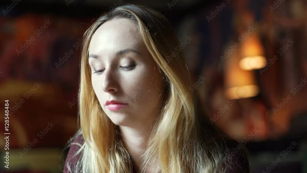 Pretty, blonde girl looking thoughtful while sitting in the murky restaurant
Pretty, blonde girl looking thoughtful while sitting in the murky restaurant