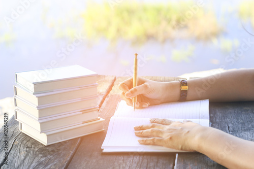 Stock Photo:.female hands with pen writing on notebook on wooden