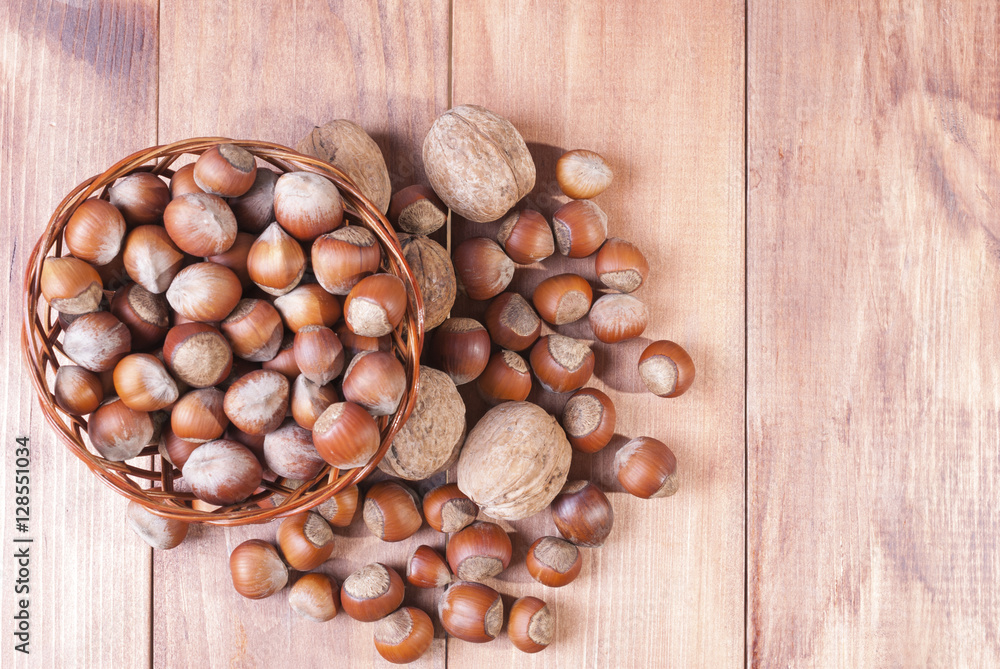 Walnuts and hazelnuts in a basket on wooden background. The view from the top. Walnuts and hazelnuts in a basket on wooden background. The view from the top.