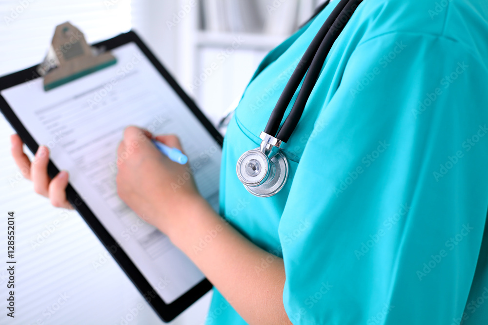 Close-up of a female doctor is filling out application form or medical history Close-up of a female doctor is filling out application form or medical history