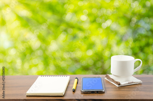 Hot coffee, smart phone, notebook and pen in nature
