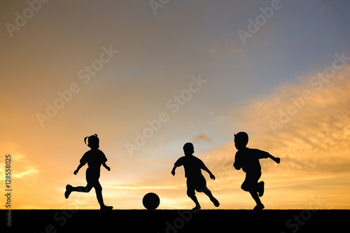 children playing soccer at sunset.