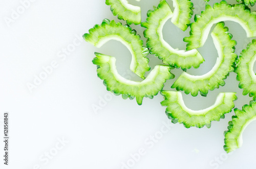 Sliced green bitter gourd or bitter melon on white cutting board ready to cooking photo