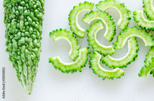 Sliced green bitter gourd or bitter melon on white cutting board ready to cooking