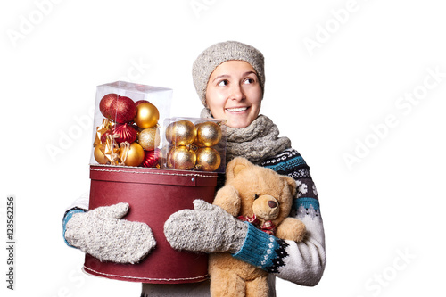 Young cute smiling girl in sweater, holding a box of Christmas decorations. Winter, Cristmastime, New Year holiday. photo