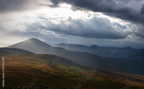 Dark mountain under a stormy evening dramatic cloudy sky with dark clouds and bright rays of sunset light Plateau Ukok Altai mountains Siberia  Russia
