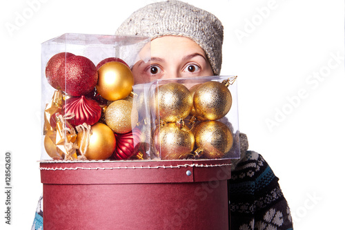 Young cute smiling girl in sweater, holding a box of Christmas decorations. Winter, Cristmastime, New Year holiday. photo