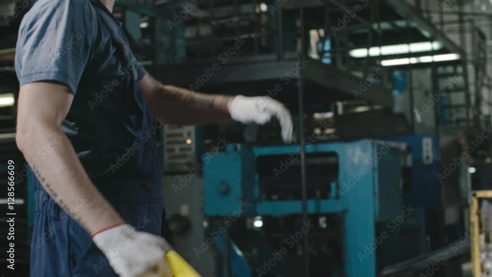 PAN of tired factory worker taking off hard hat and wiping his forehead with hand, then looking at camera PAN of tired factory worker taking off hard hat and wiping his forehead with hand, then looking at camera