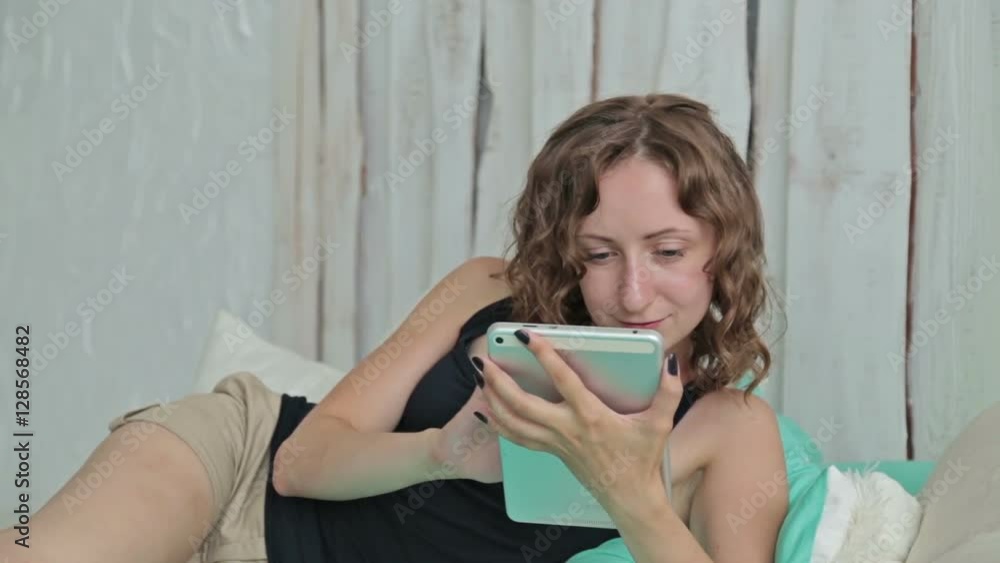 Young curly woman lying in the bed with tablet pc (smiling, scrolling and touching) Young curly woman lying in the bed with tablet pc (smiling, scrolling and touching)