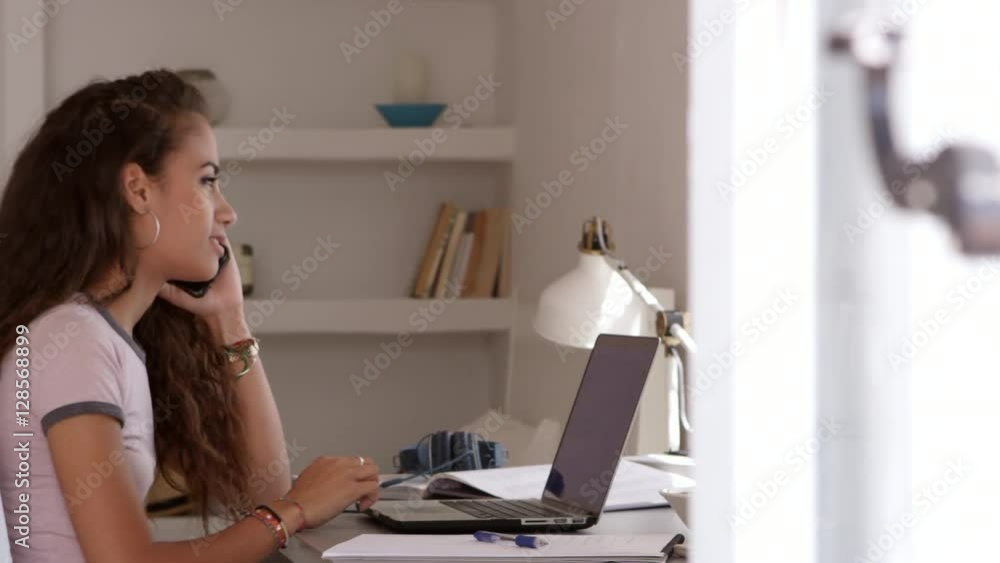 Girl using laptop in bedroom takes a call on her phone, shot on R3D Girl using laptop in bedroom takes a call on her phone, shot on R3D